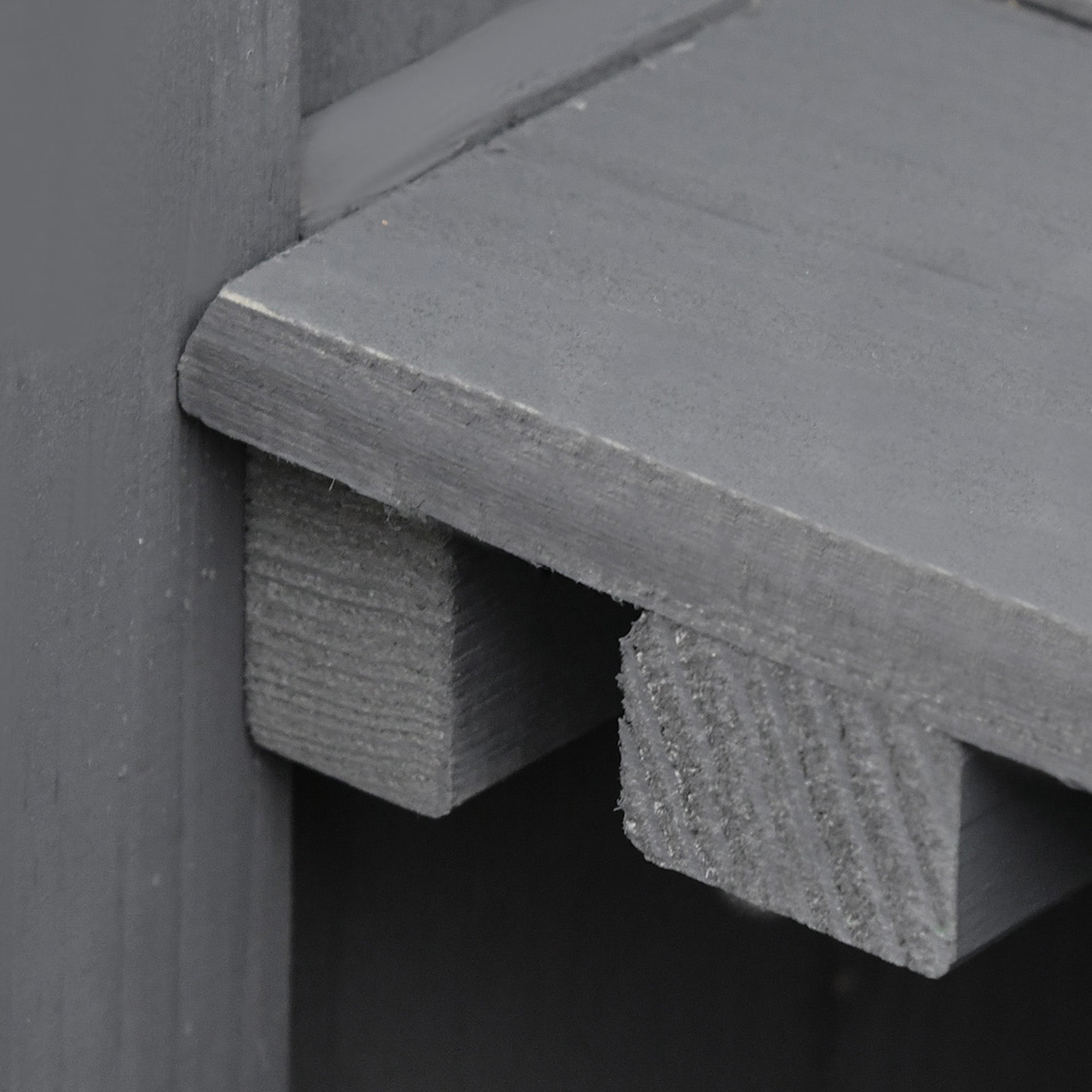 Gray wooden garden storage shed corner with visible grain and hinged roof for outdoor garden storage
