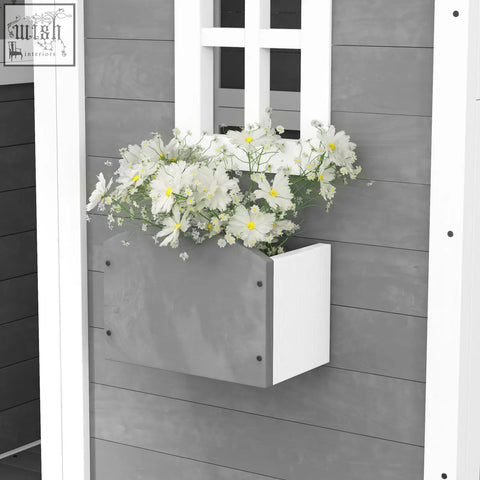 Grey wooden kids playhouse with white rectangular plant box filled with daisies and inside flooring for gardens