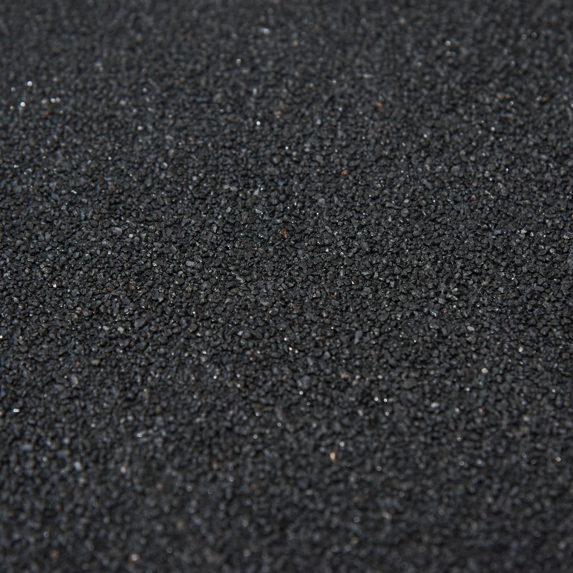 Black rubberized gravel with a coarse texture used for garden tool storage outside the outsunny wooden small shed 75l x 56w