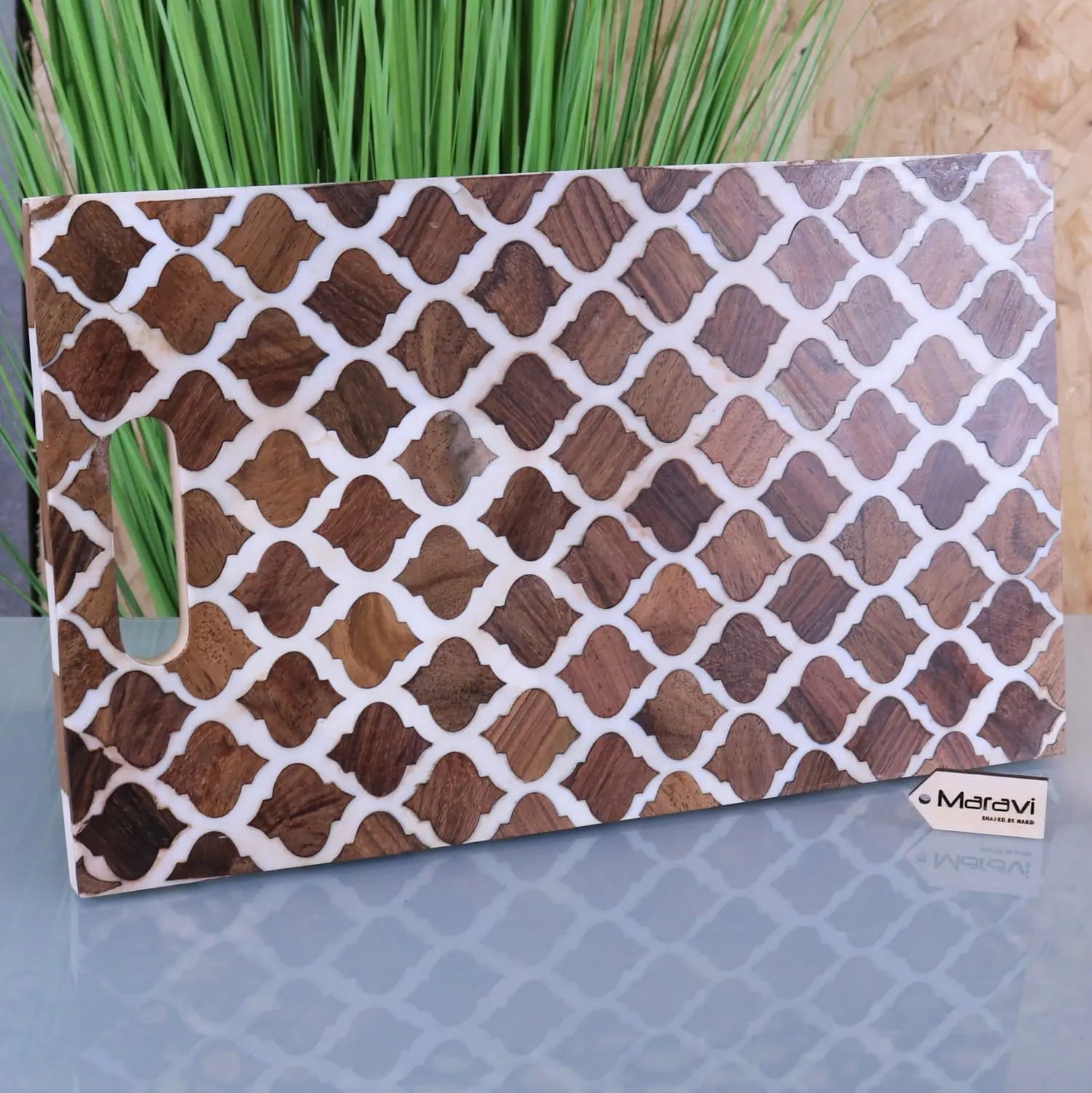 A rectangular ouzoud moroccan serving platter board with dark brown wood lattice inlays on a wooden cutting board