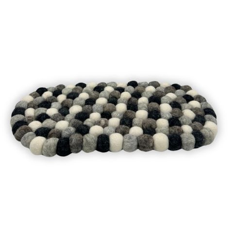 A cozy oval felt ball centre mat made from black white and gray woolen balls in a textured pattern