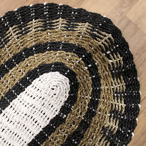 Oval seagrass woven rug in black white and tan with a classic circular pattern 60x120cm
