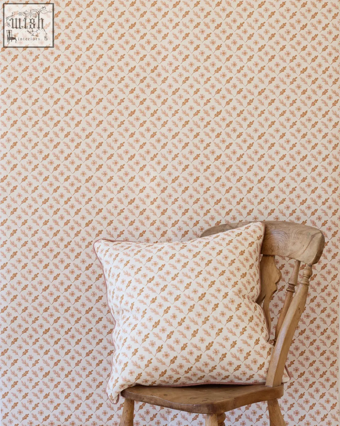 A soft off-white cushion with muted peach and brown botanical rippled leaves rests on a rustic oxalis oak wooden chair