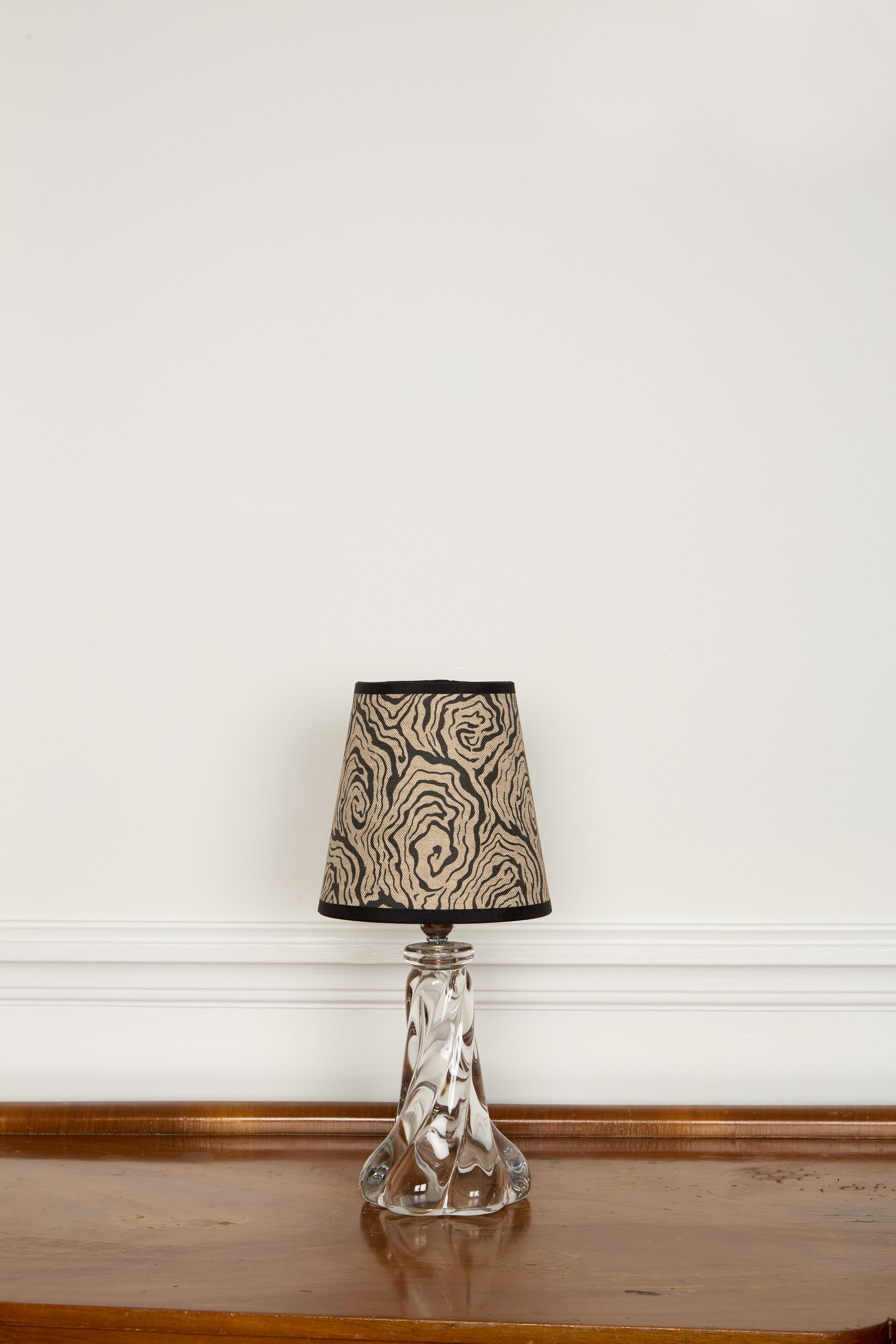A clear glass table lamp with a faceted base and an ornate swirling beige and black oysters monochrome lampshade