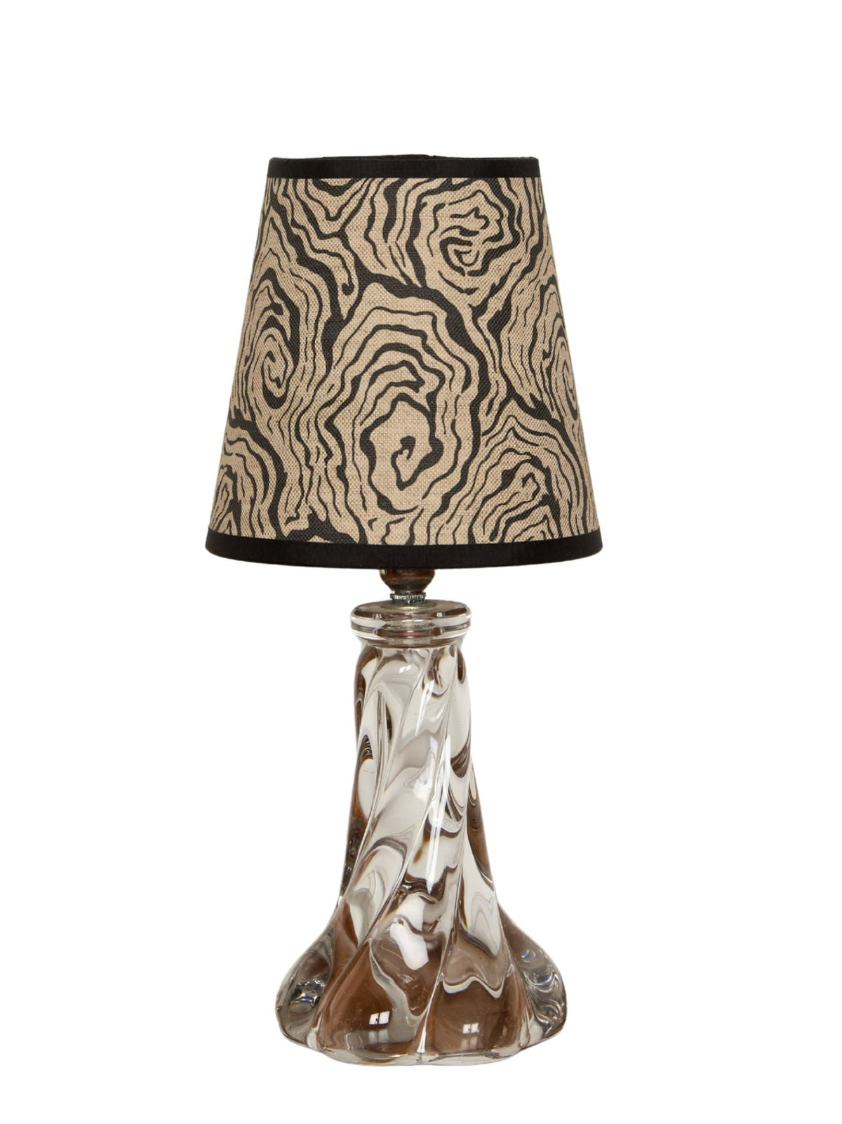A clear glass table lamp with an intricately twisted base and oysters monochrome beige and black patterned shade