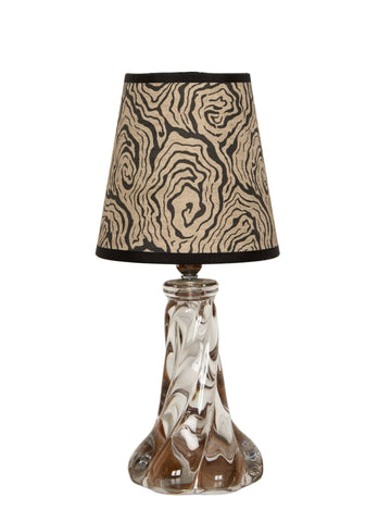 A clear glass table lamp with an intricately twisted base and oysters monochrome beige and black patterned shade