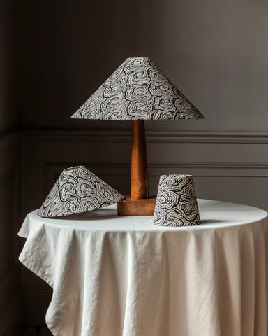 A black and white swirl patterned oysters monochrome tapered cone lampshade with a wooden base