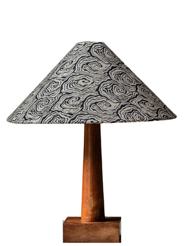 A large tapered cone lampshade with a black and white swirling pattern on a slender wooden stand