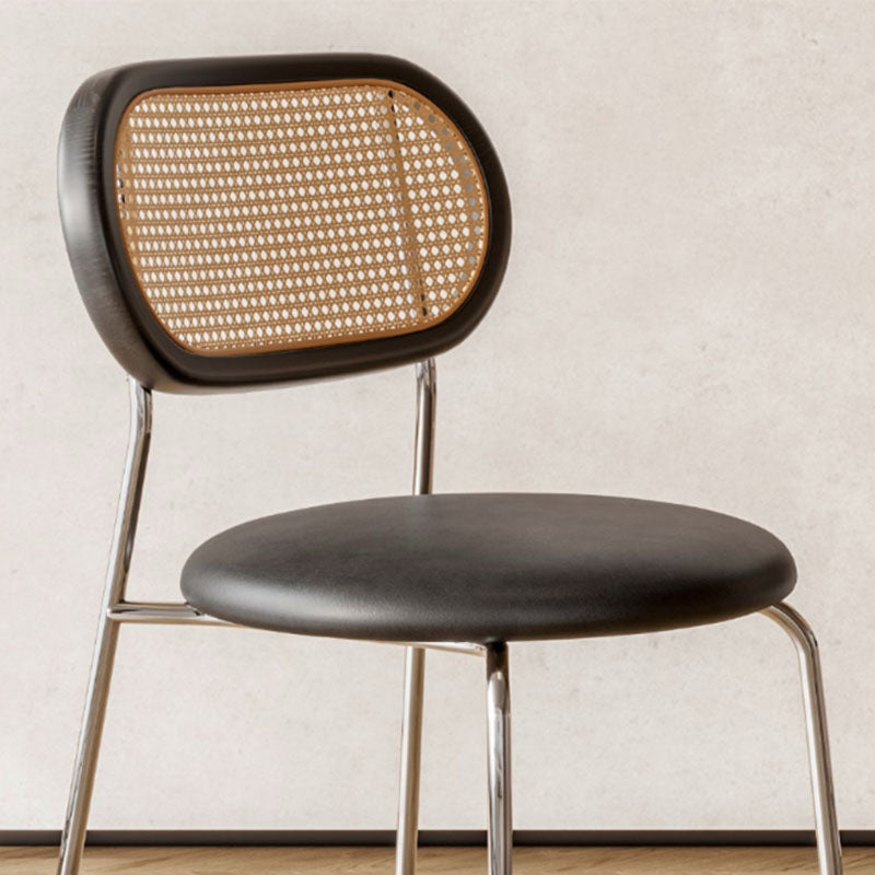 Ozzie rattan dining chair with black leather seat and backrest featuring woven cane panel and chrome legs