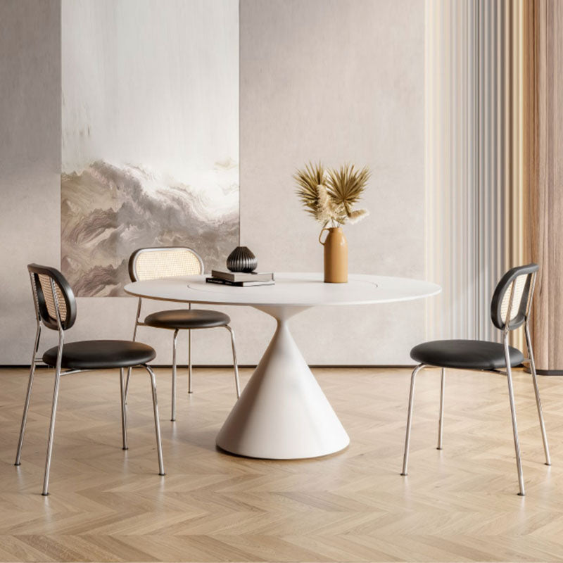 White pedestal dining table with a sleek modern design and smooth surface paired with ozzie rattan dining chair
