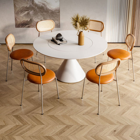 White round dining table with conical base and rotating surface paired with ozzie rattan dining chair