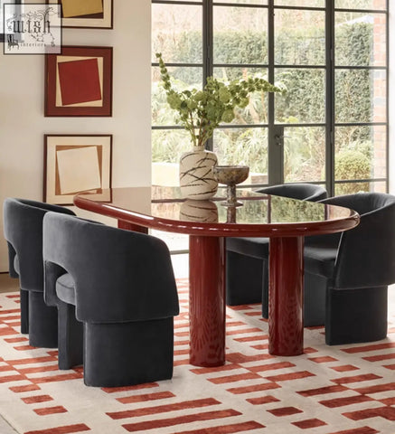 A glossy red marble dining table with curved edges and sculpted pedestal legs pairs perfectly with dining chairs