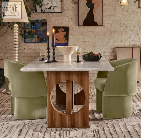 Marble dining table with a wooden base featuring vertical grooves and a circular cutout paired with paddy velvet dining chair