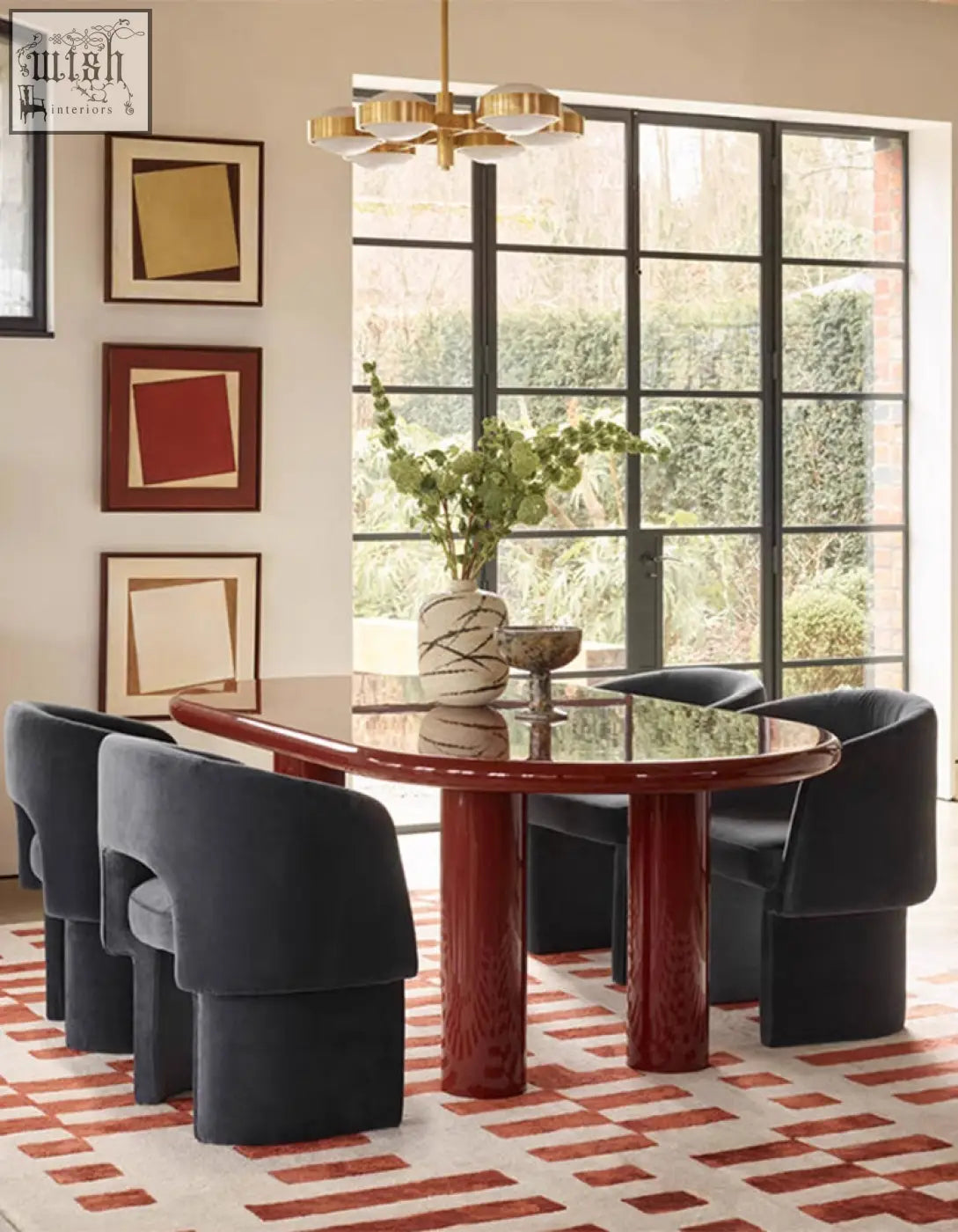 The paddy dining chair in velvet paired with a sleek red marble dining table featuring sculpted cylindrical legs