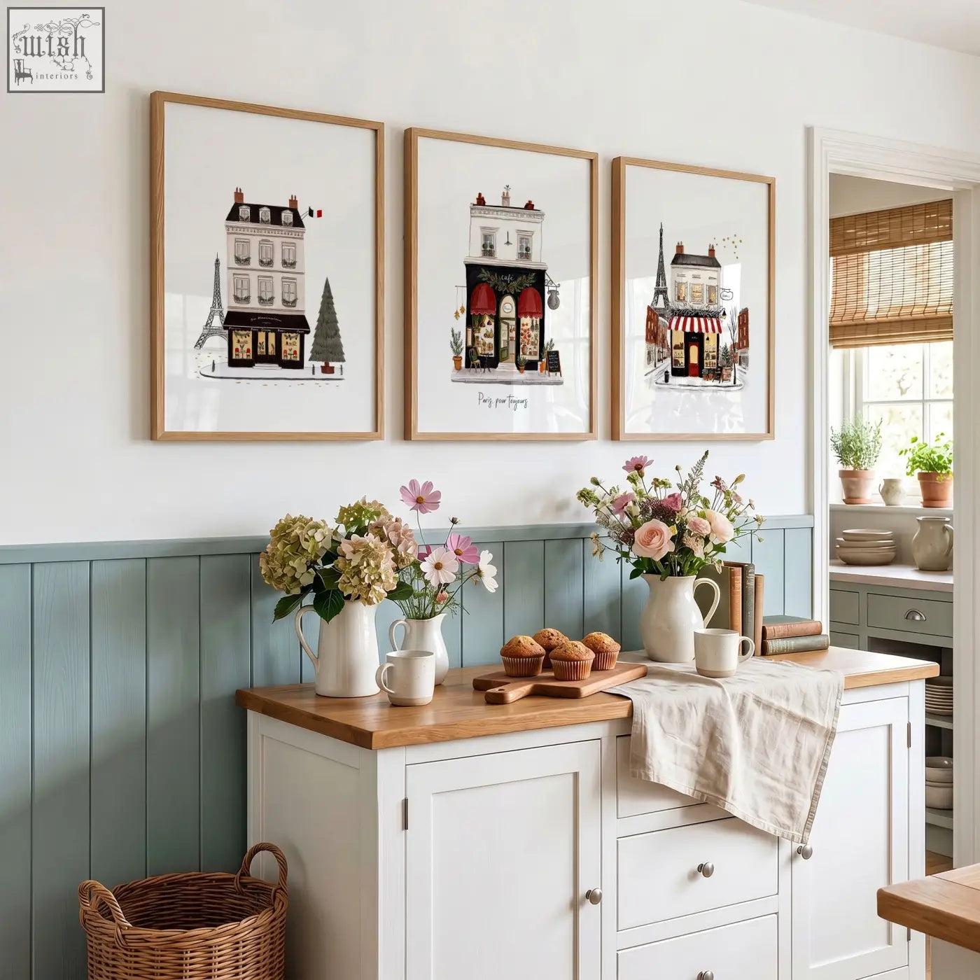 Three framed parisian-themed street scenes wall art with light wood frames above blue cabinet featuring pour toujours design