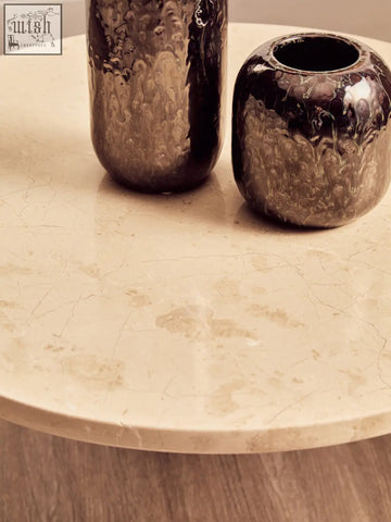 Two dark metallic vases with hammered texture on a round cream marble top small coffee table called palermo