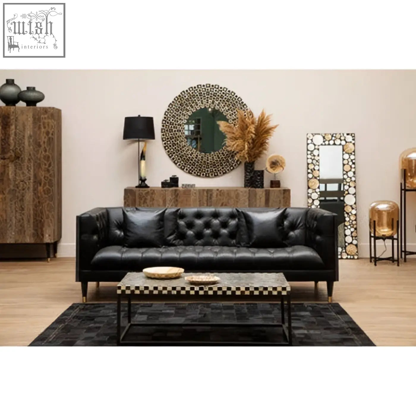 Black tufted leather sofa with modern legs paired with a palu round black wall mirror with shell inlay