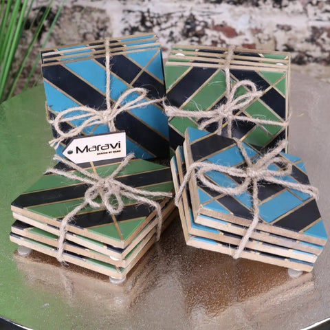 Set of four panna luxe resin coasters with teal black geometric pattern and gold trim tied with rustic twine