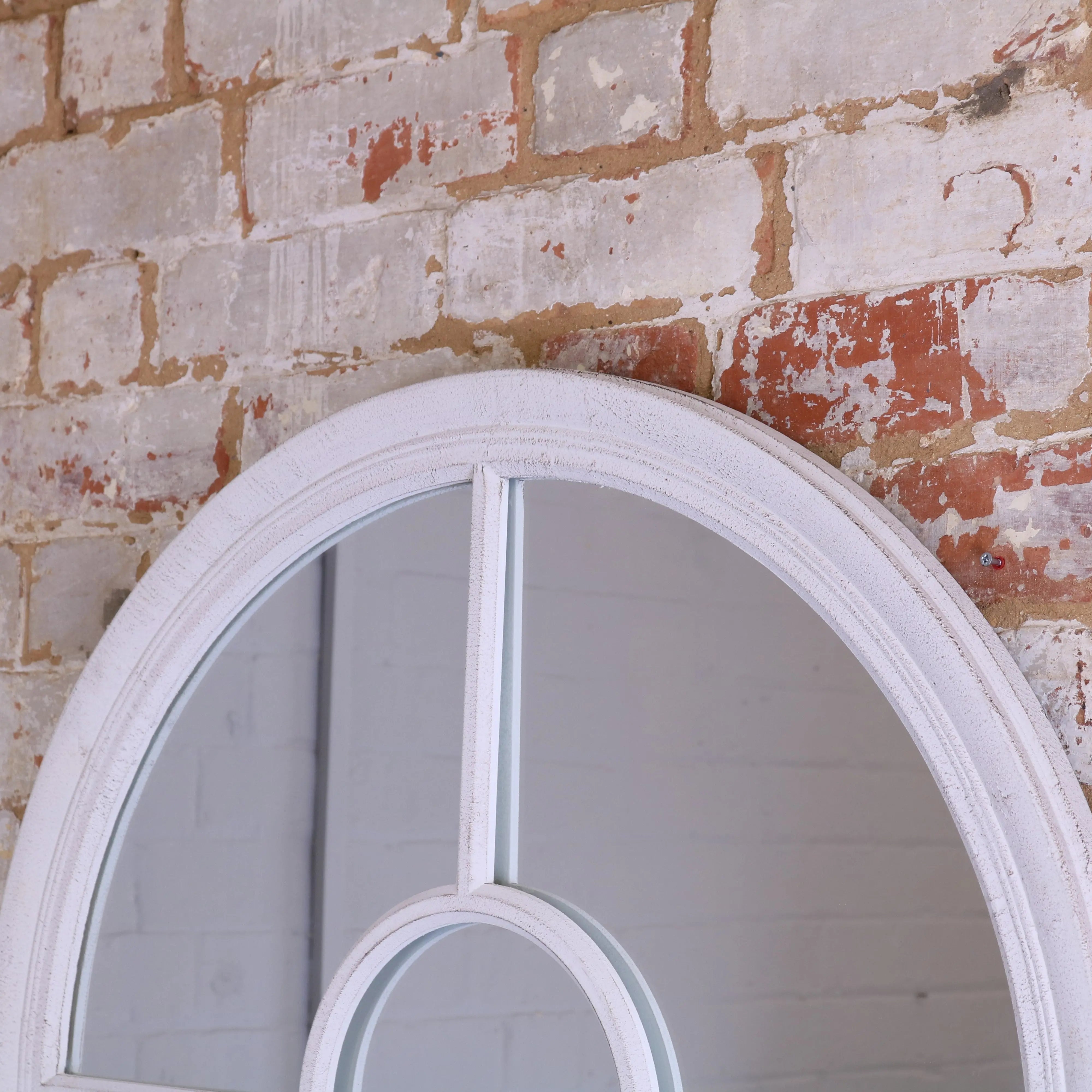 White distressed oval window style mirror with arched frame and geometric glass panel design in rustic style