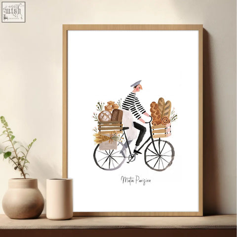 A framed watercolor wall art in brown tones showing a man in a striped shirt riding a bread-loaded bike matin parisien style