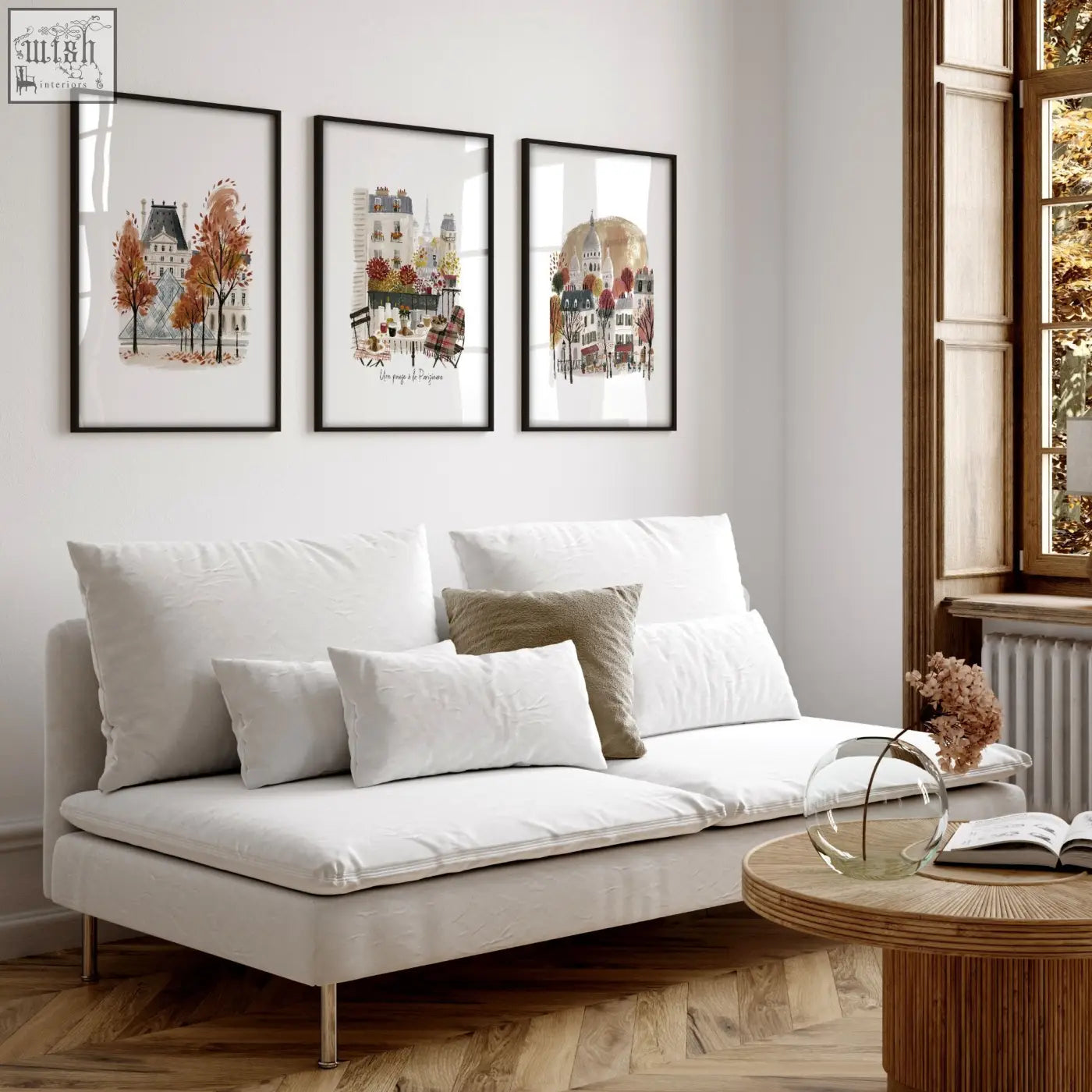 White upholstered sofa with metallic legs and cushions in a living room featuring paris travel wall art prints set