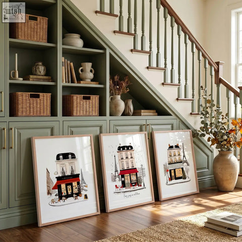 Three parisian-themed wall art pieces with illustrated street scenes leaning against a green cabinet under stairs