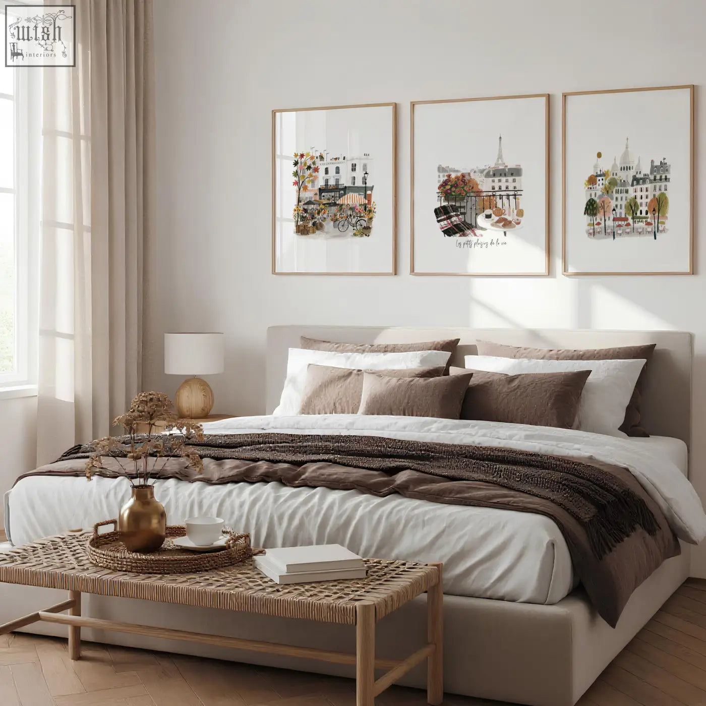 Beige upholstered bed with layered white and brown bedding beside paris wall art autumn watercolour scenes set of 3