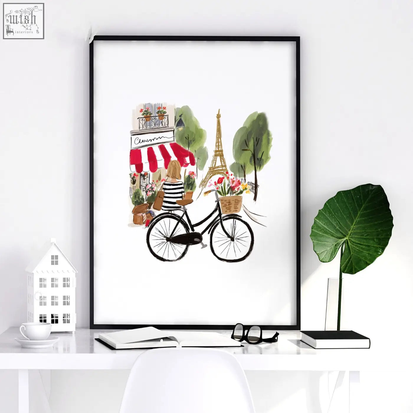 Black-framed paris wall art featuring a woman on a bicycle with eiffel tower and café in a floral basket design