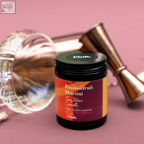 A dark glass jar passionfruit martini apothecary candle with orange maroon label black lid made from sustainably sourced soy wax