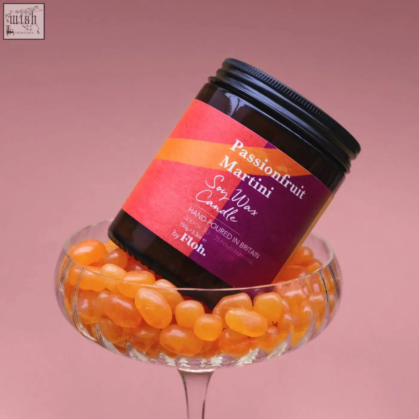 A vibrant orange and purple passionfruit martini soy wax candle in a dark glass jar with a long burn time and sustainably sourced ingredients