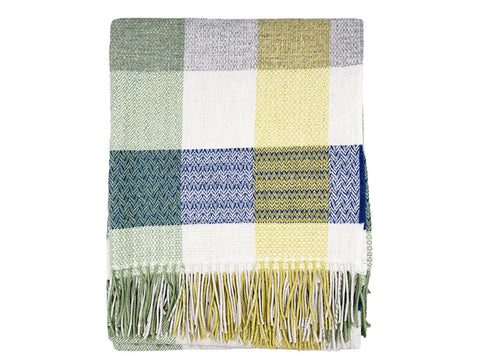 A soft patchwork merino lambswool throw in muted greens creams blues and yellows with herringbone texture