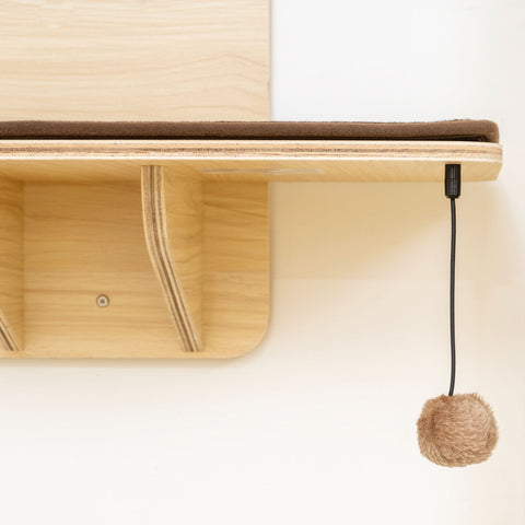 Pawhut light wood cat shelf with brown cushioned top and fuzzy pom-pom toy is a mounted cat tree with washable plush mats