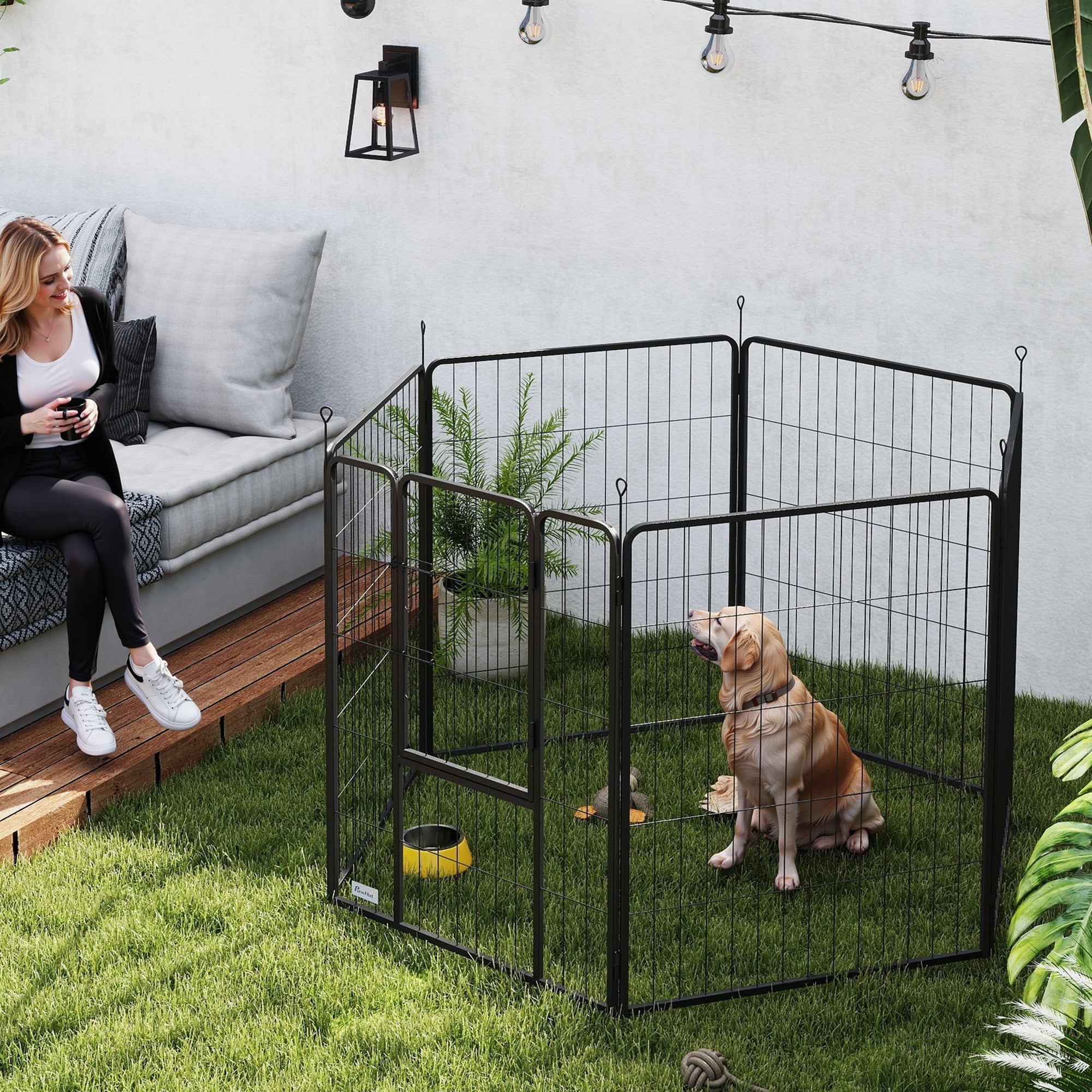 Black metal dog pen with wire mesh panels and small yellow bowl inside portable for large dogs with ground stakes