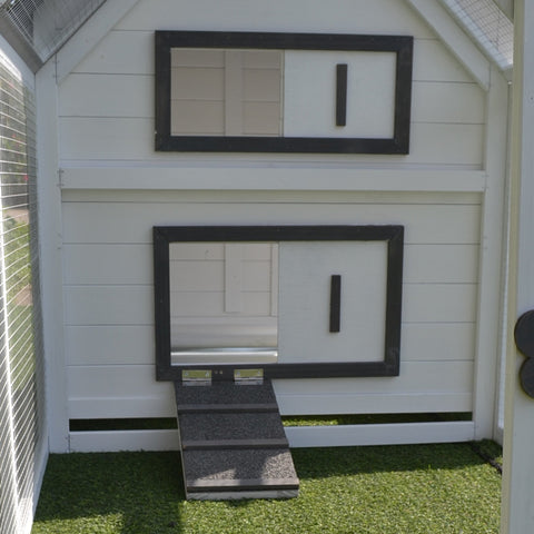 White fir wood chicken coop with black-framed windows sliding door and nesting box with small ramp entrance