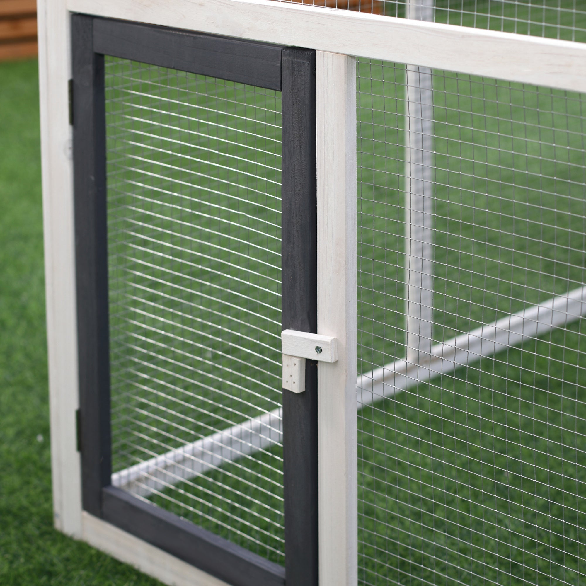 White and black framed mesh door with white latch on fir wood chicken coop with nesting box for outdoor pets