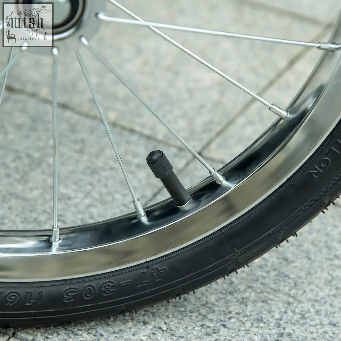 Black rubber tire valve stem with textured grip cap on chrome wheel rim of pawhut dog pram with three large rubber wheels