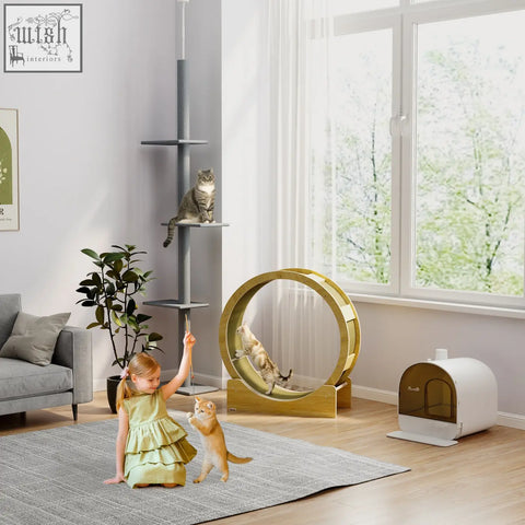 Gold-colored wooden cat exercise wheel with circular slats next to pawhut hooded cat litter box with lid and scoop