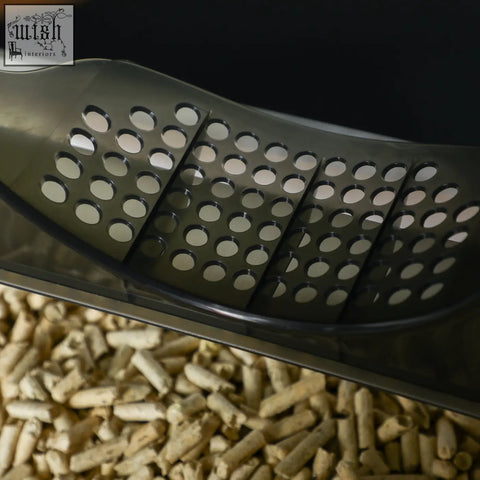 Black perforated plastic scoop resting on light brown wood pellets in pawhut grey cat litter box with hooded design