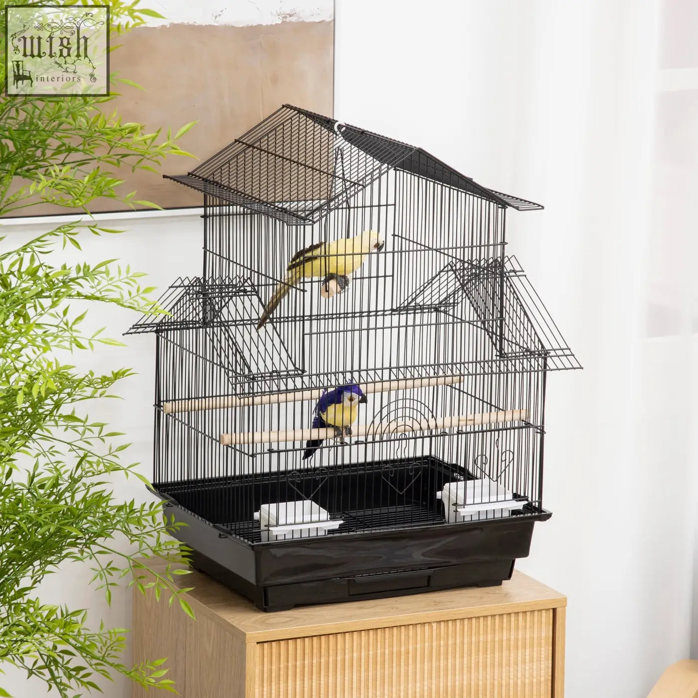 Black metal bird cage with house-shaped roof and plastic food containers housing colorful feathered friends