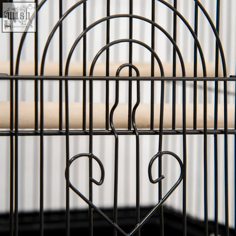 Black metal bird cage with heart accents wooden perches plastic food containers for feathered friends like finch and budgie