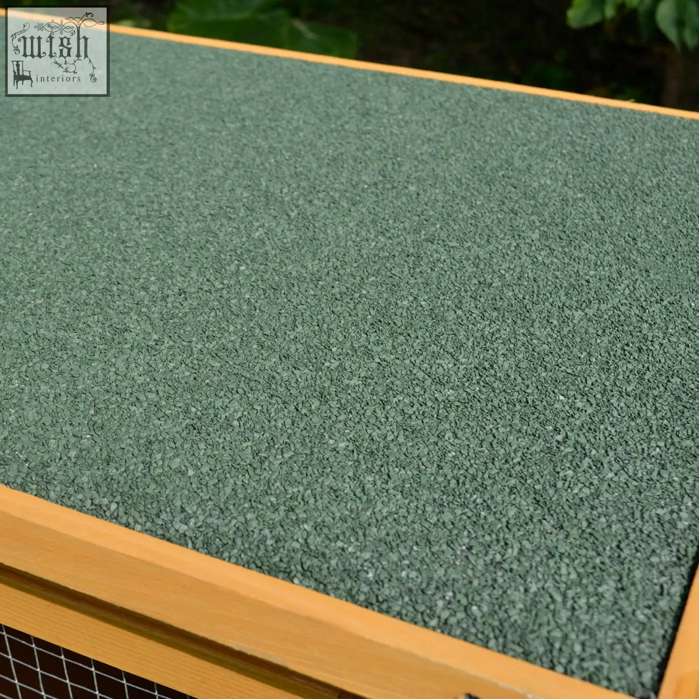 Green rubberized textured surface framed by light fir wood in a rabbit hutch for small animals outdoor use