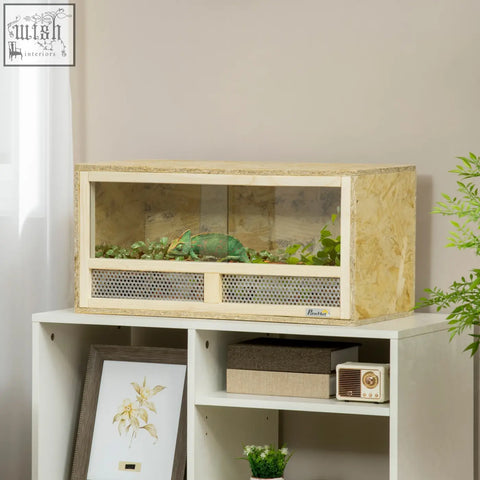 A light wood-finished pawhut reptile terrarium with breathable mesh panels and sliding doors housing a green chameleon