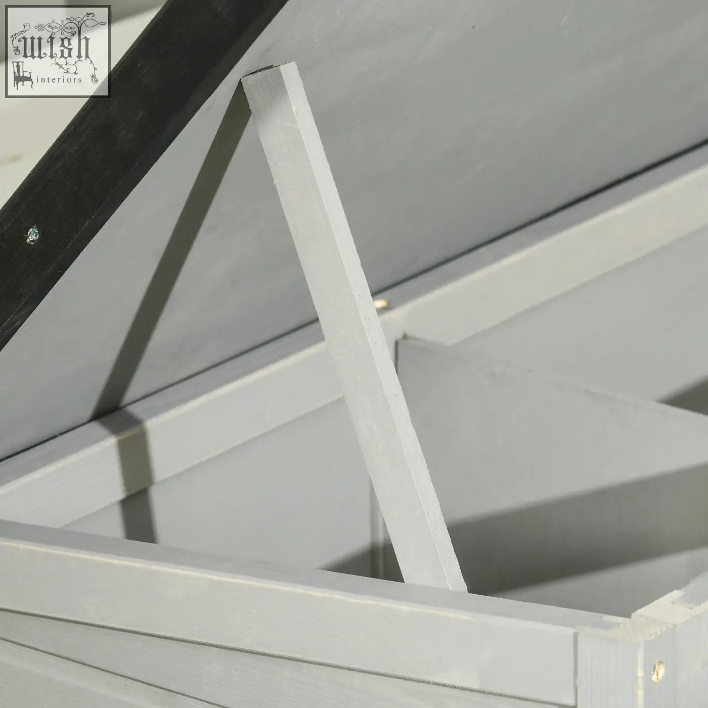 White painted wooden support beam with black diagonal brace on the back of pawhut guinea pig hutch with asphalt roof