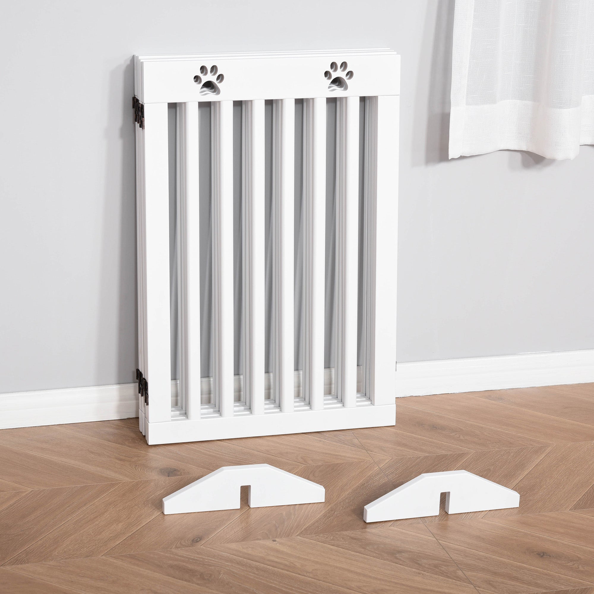 White wooden pet gate with paw print cutouts and foldable freestanding design with matching support feet