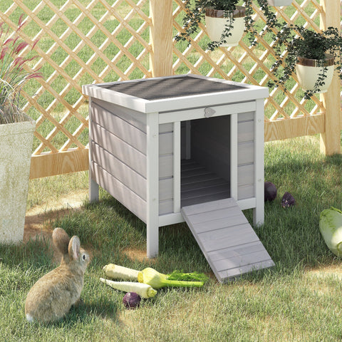 Gray wooden rabbit hutch with asphalt roof and slanted door ramp for outdoor guinea pig or bunny house