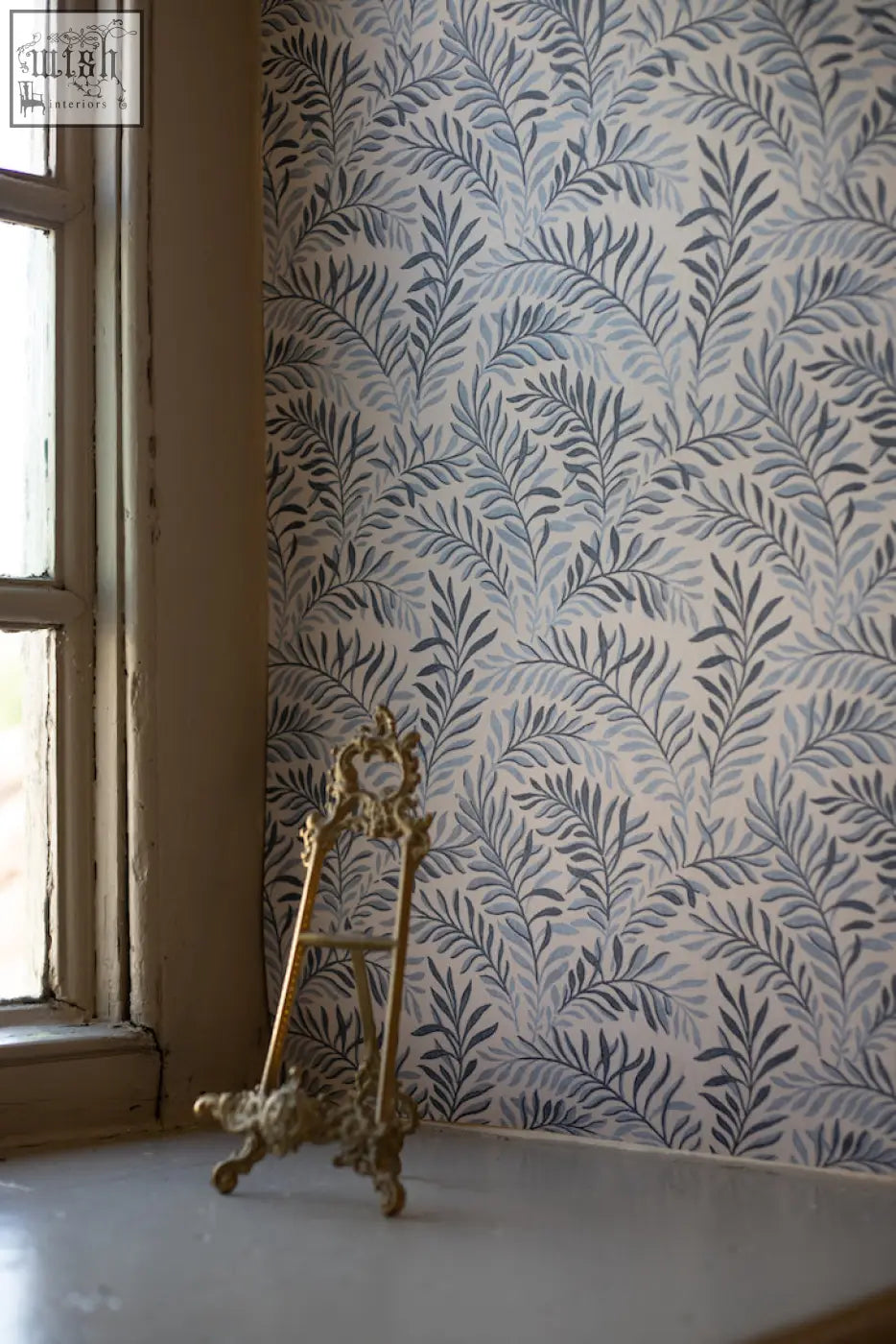 Antique gold-colored ornate easel with art nouveau dancing leaves design holding peace in blue hues wallpaper made from ethically sourced materials