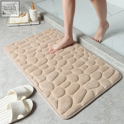 Beige pebble stone bathroom floor mat with soft plush memory foam surface and rounded edges for water absorption