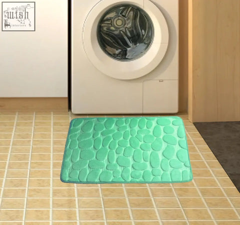 A mint green pebble textured memory foam floor mat with soft plush surface for bathroom water absorption use