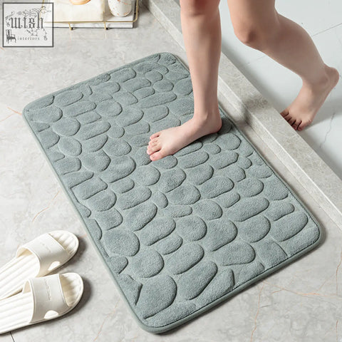 A soft slate-gray pebble floor mat with plush memory foam for water absorption perfect for bathroom or toilet use