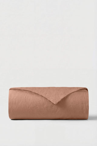 A neatly rolled terracotta percale duvet cover made of soft linen with a textured surface and clean fold
